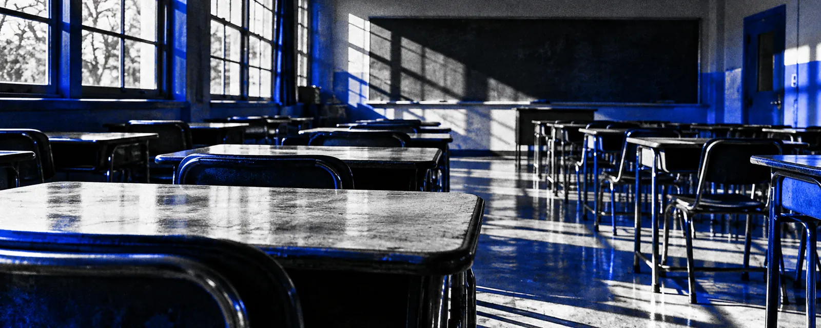 Empty classroom desks in window light, in cobalt duotone.